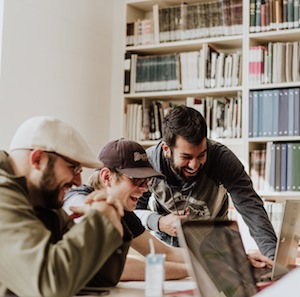 Three Casually Dressed Guys Smiling Around Computer