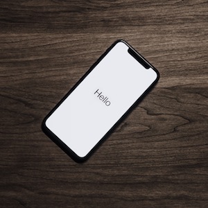 Phone On Wood Surface With White Screen Saying "Hello"